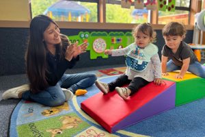Preschool educator providing individualized attention and hands-on learning support to young children in a caring classroom environment