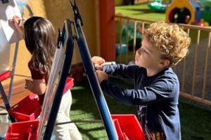 Child painting at an outdoor easel in the ECO-Art Studio at Academy on the Hills