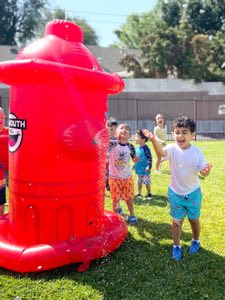 Children enjoying sprinkler play and water slides during summer activities at Academy on the Hills